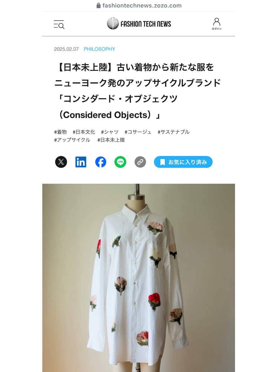 A white long-sleeve button-up shirt dress with silk kimono-pressed flowers displayed on a mannequin against a plain beige wall. The image is taken from a Japanese fashion news webpage titled 'Considered Objects'.