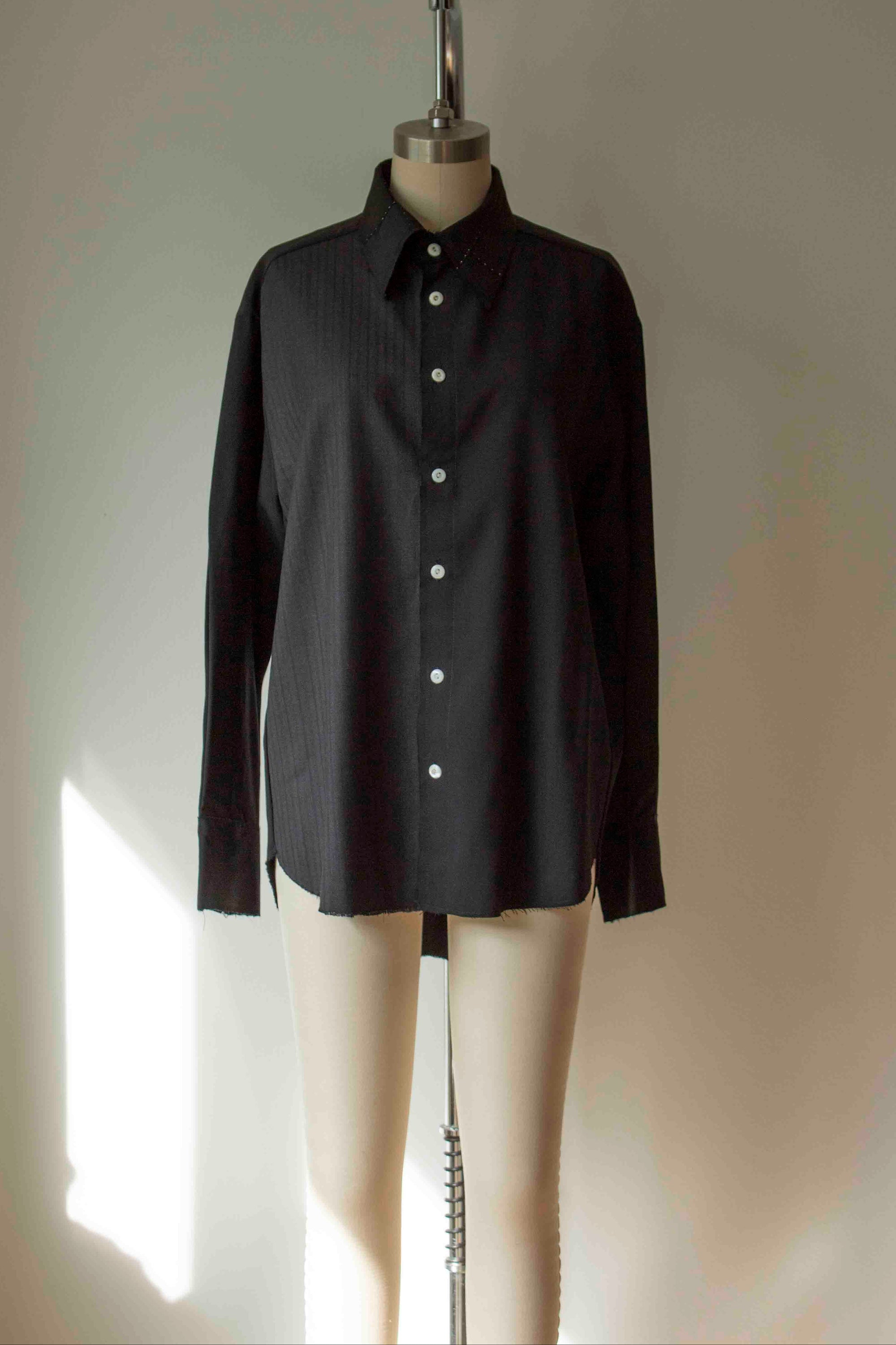 Black shirt on a mannequin against a plain background