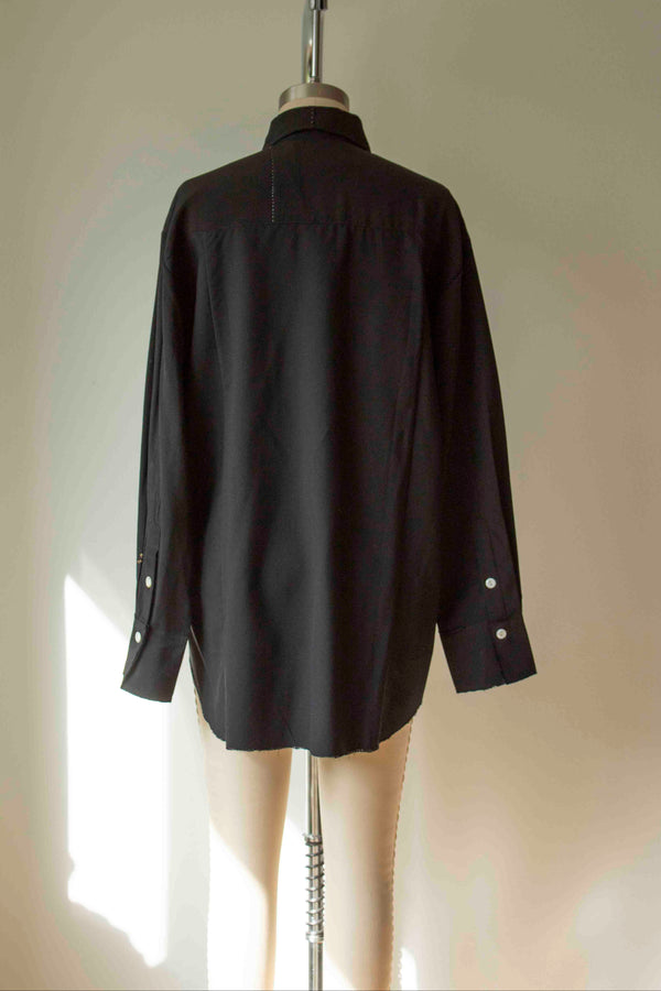 Black shirt on a mannequin against a plain background