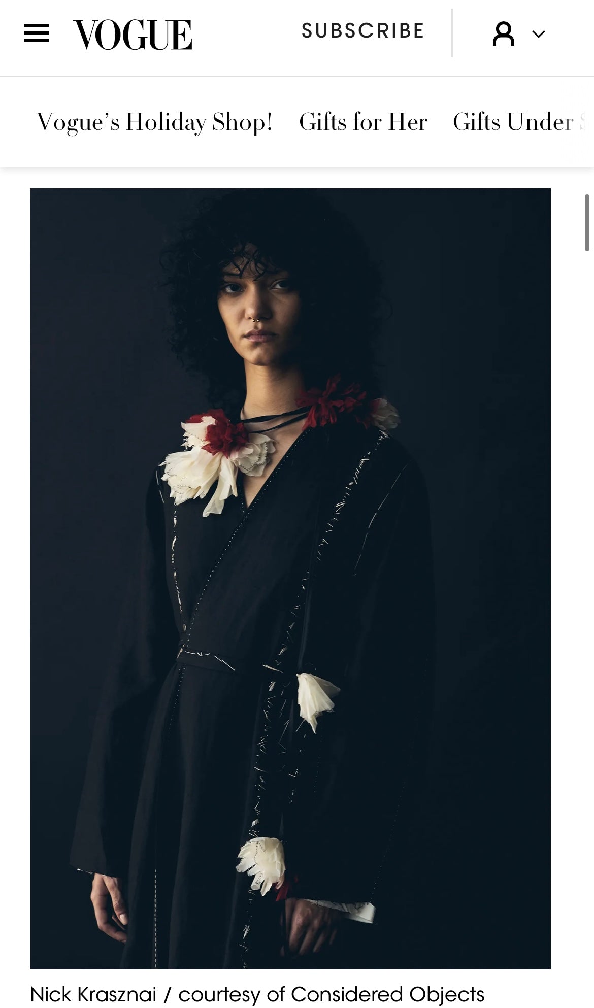 A fashion editorial photo from Vogue featuring a model with dark curly hair wearing the irregular wrap dress and ume red/yuki white falling flower accessory from Considered Objects.