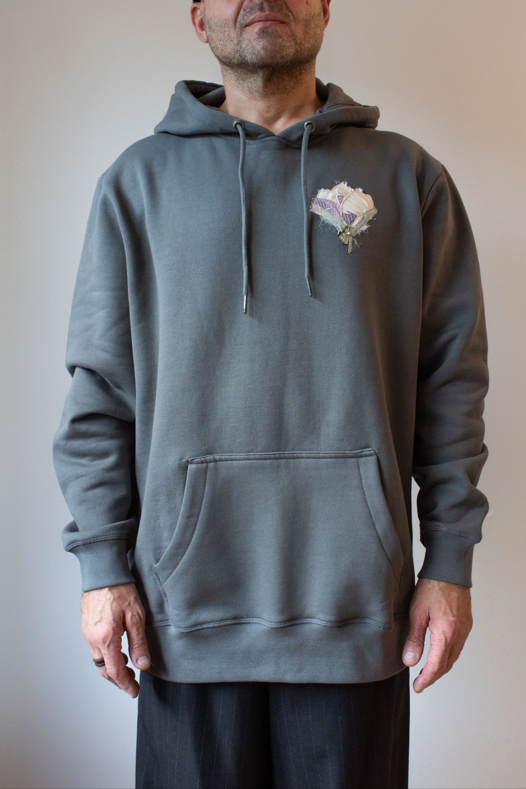 Man wearing a gray hoodie with a floral design on a plain background