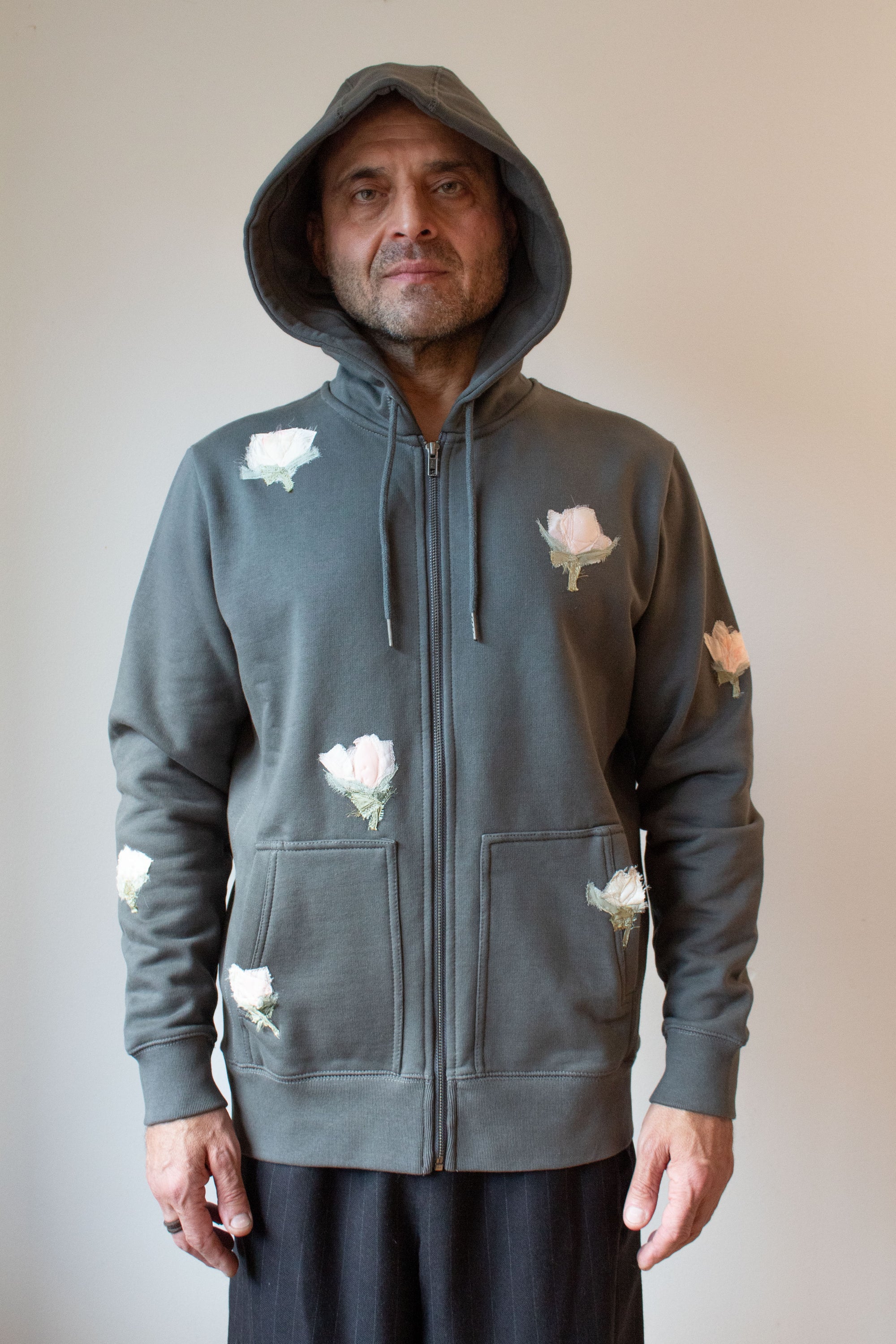 Man wearing a gray hoodie with floral designs on a plain background