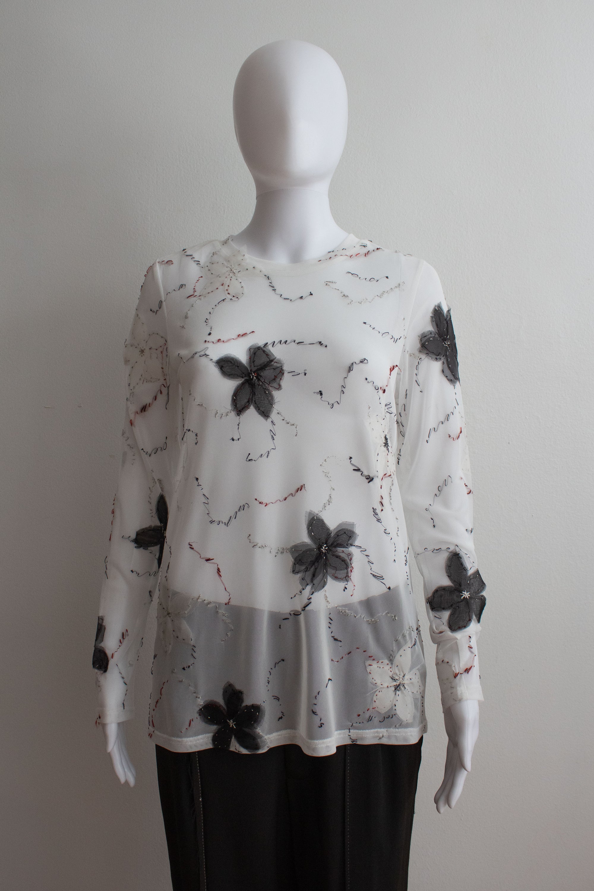 White floral-patterned blouse on a mannequin against a plain background