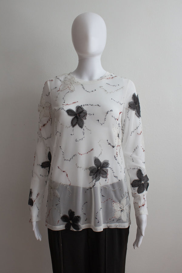 White floral-patterned blouse on a mannequin against a plain background