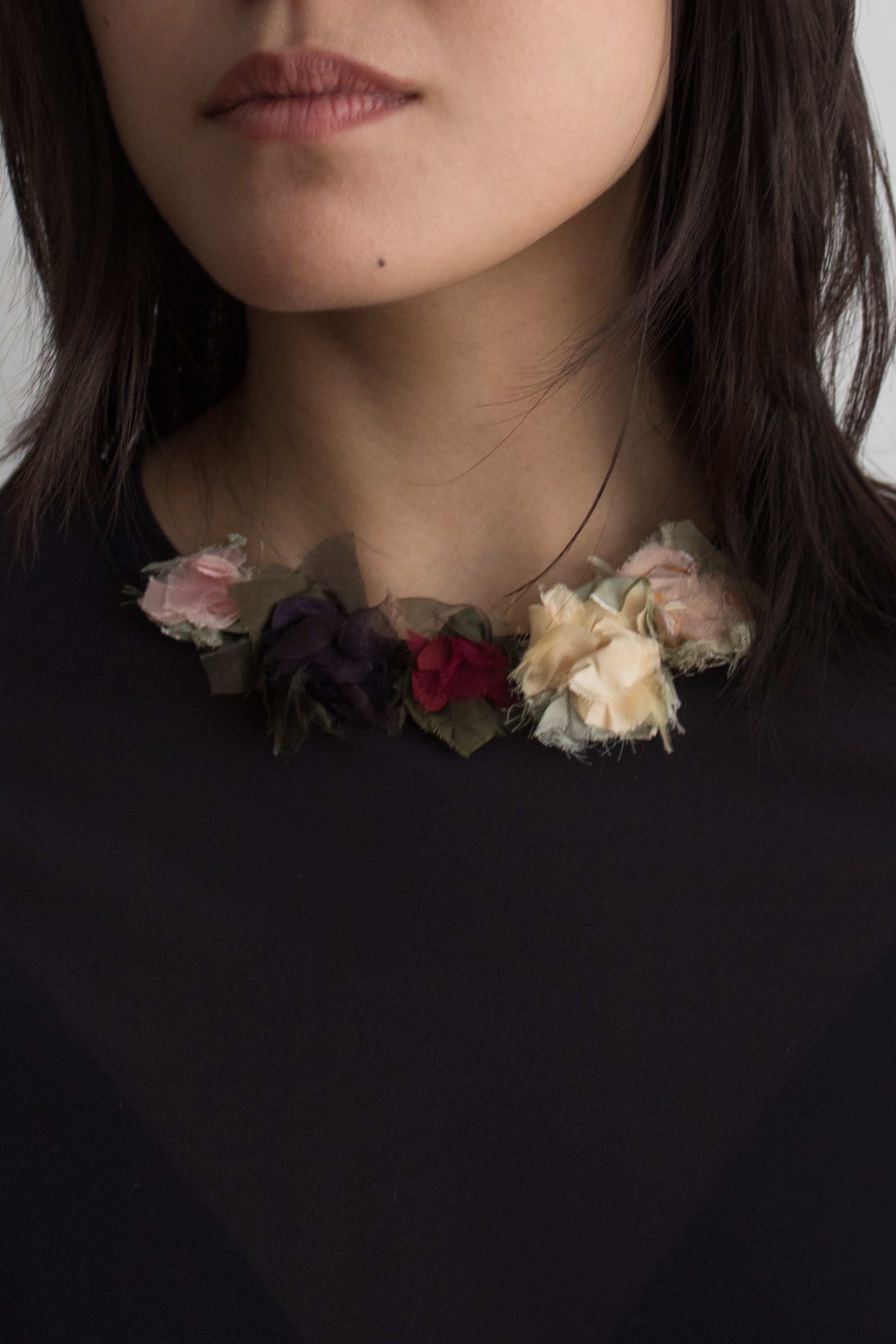 Floral collar necklace worn by a person against a neutral background