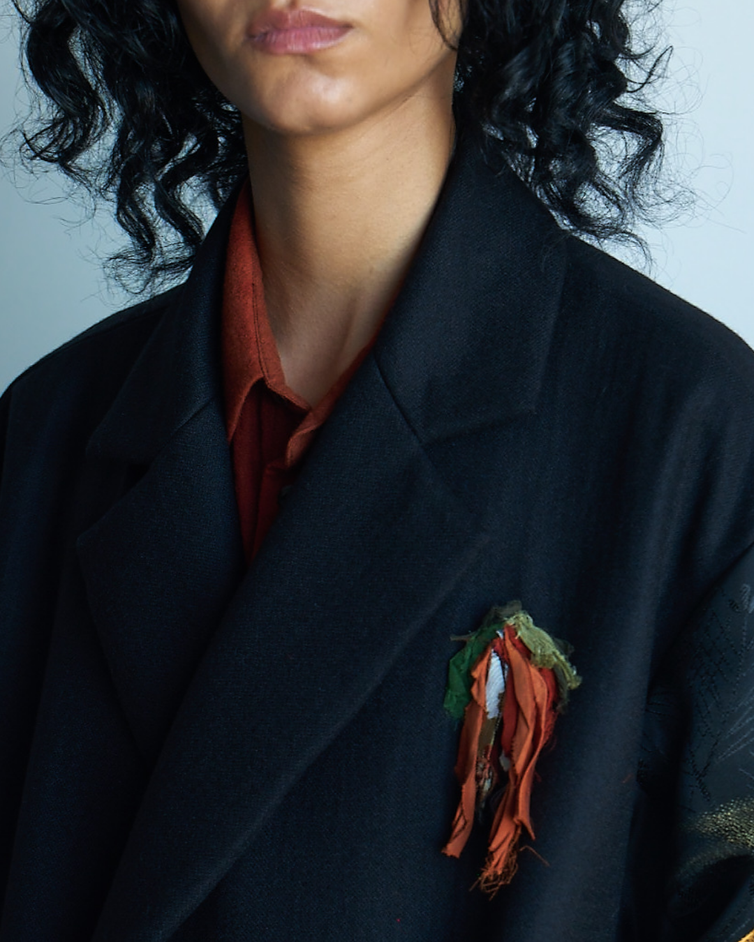 orange silk petal brooch on black wool coat
